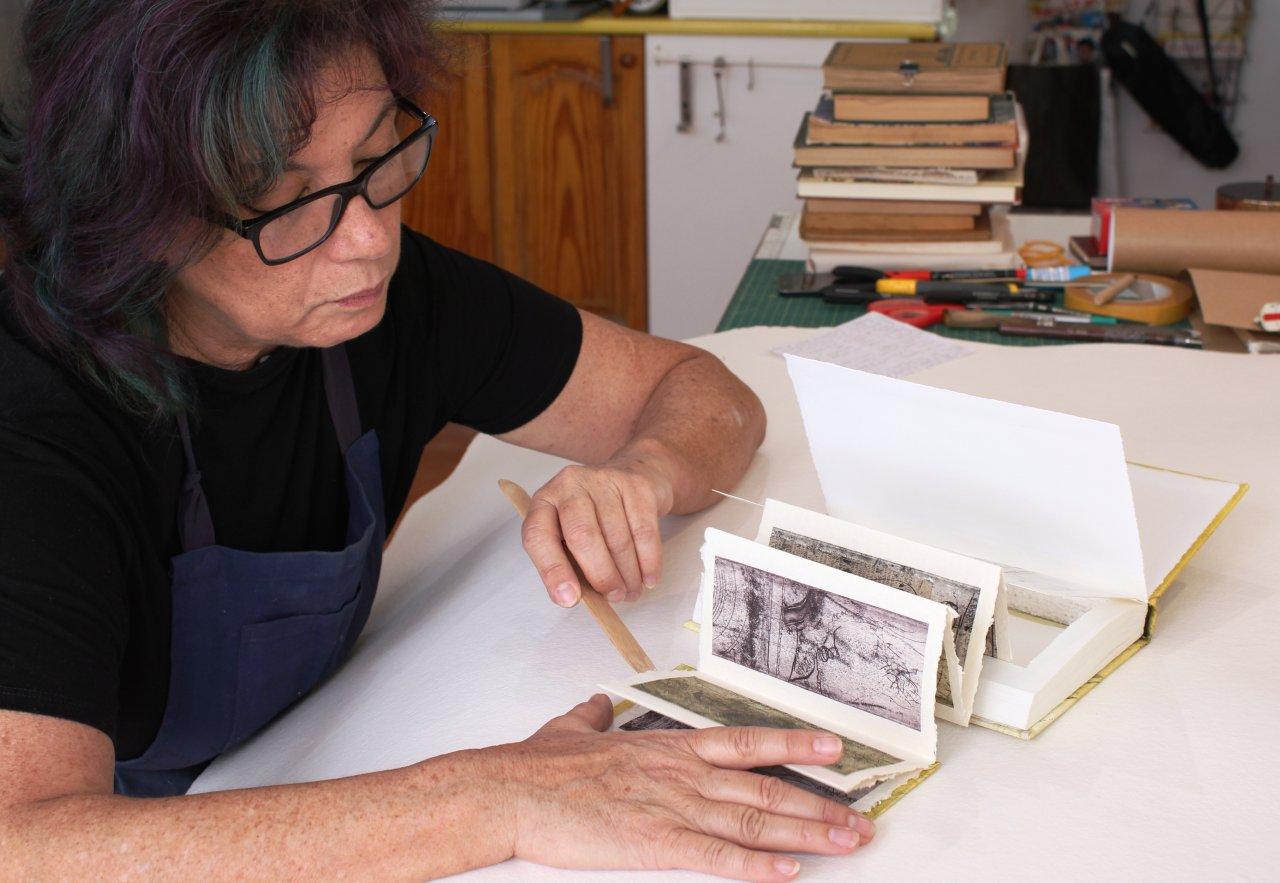 La artista Paqui Martín trabajando en uno de sus libros alterados